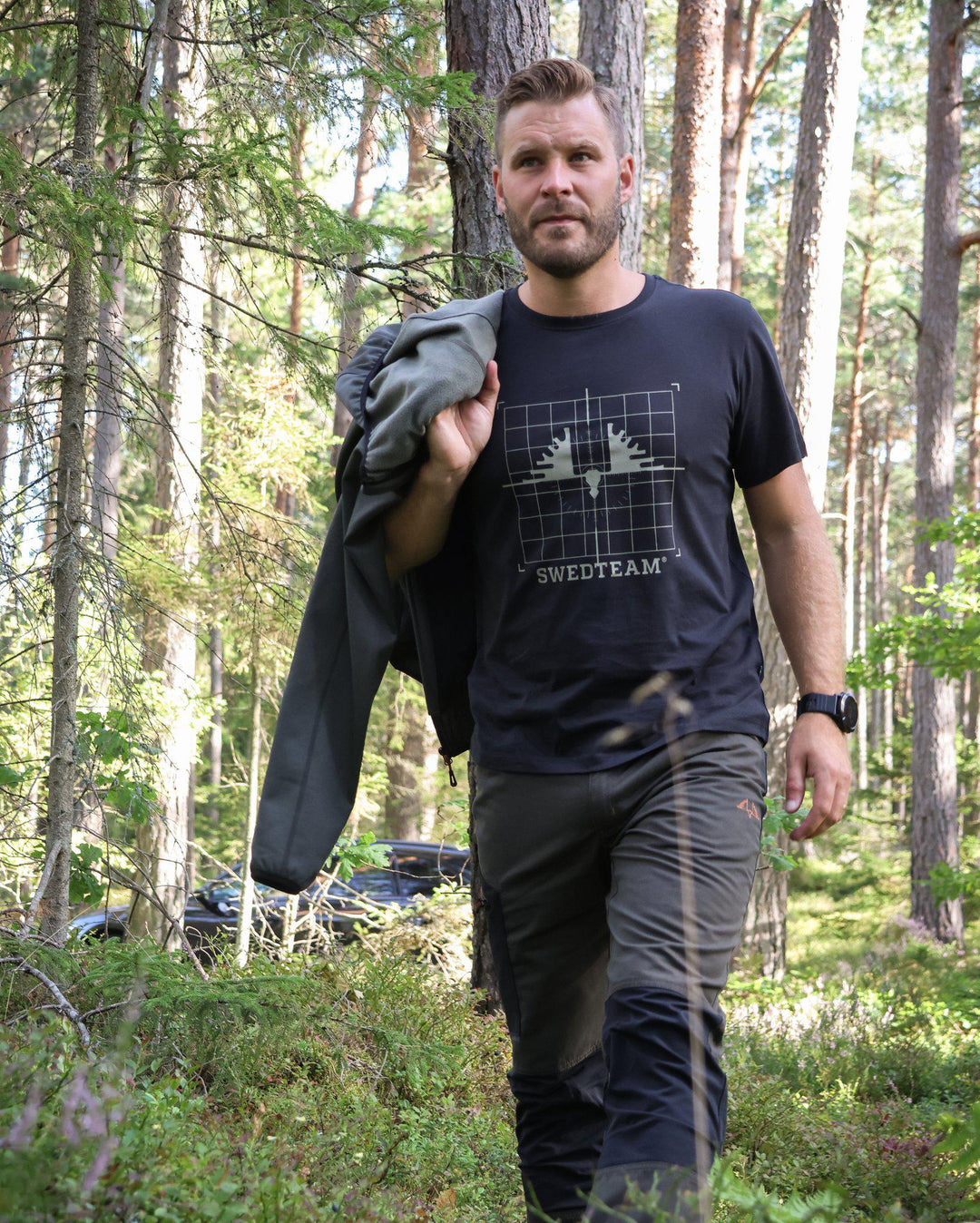 Man i svart Swedteam t-shirt under promenad i skogen – bekväm t-shirt för jakt och friluftsliv.