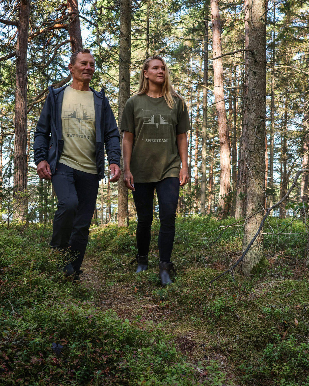 Man med beige t-shirt med Swedteam-tryck i skogsmiljö.
